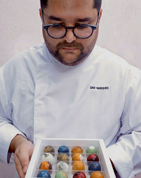 Daniel Marques segurando uma caixa de bombons coloridos